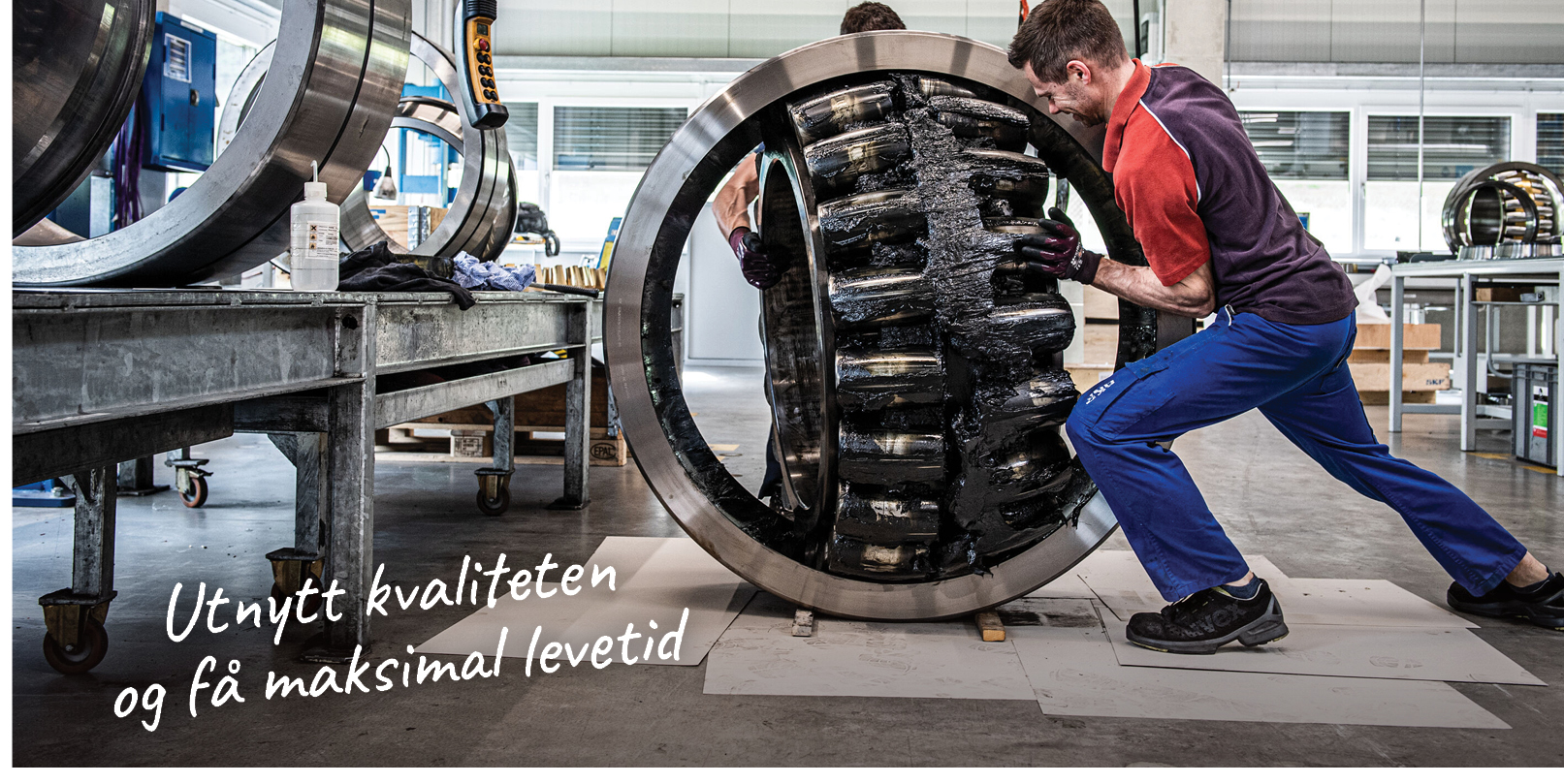 Et digert og tungt kulelager for industribruk håndteres av to arbeider hos SKF.