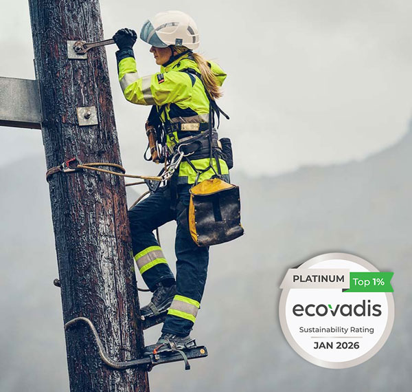 Kvinne med verneutstyr i høyspentmast